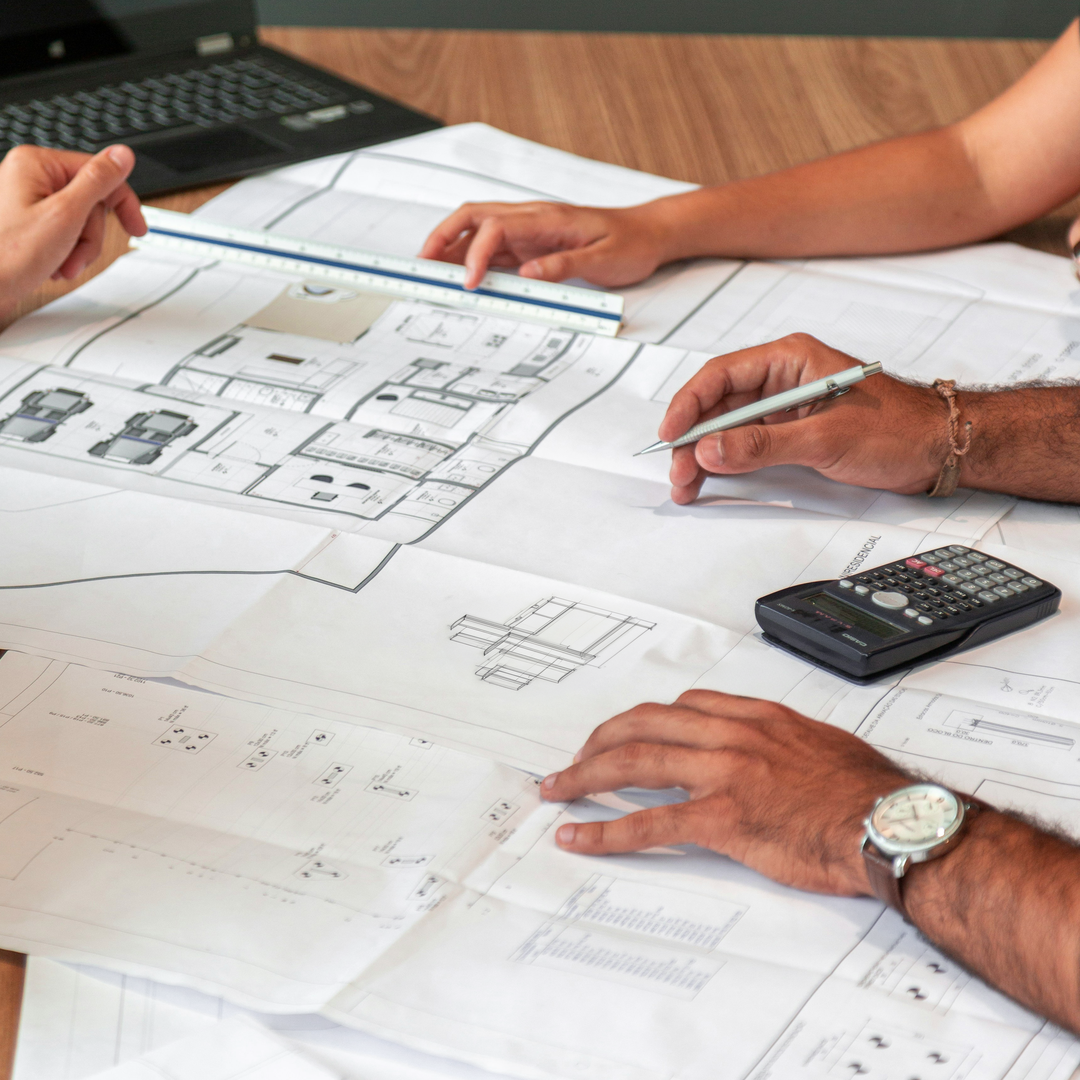 Architekt zeigt auf einem Grundriss die effiziente Raumaufteilung eines Mehrfamilienhauses in Münster.